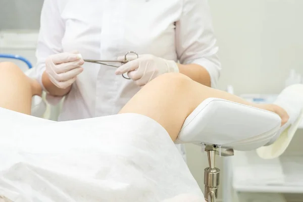 Gynekologický lékař vyšetřující pacientku na gynekologickém křesle držící kleště — Stock fotografie