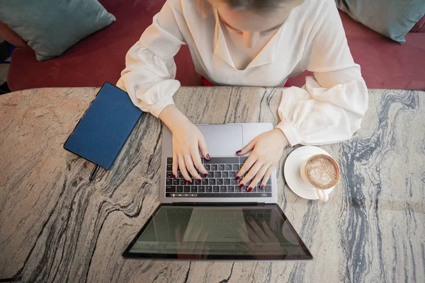 Eine junge attraktive Geschäftsfrau sitzt mit Laptop und Kaffee in einem Café — Stockfoto