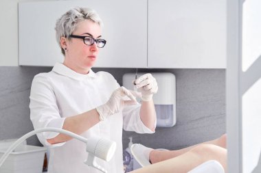 Şırıngalı jinekolog, jinekoloji koltuğundaki hastaya iğne yapıyor.