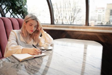 Hayalperest genç kadın not defteriyle yazıyor, boşluğu kopyala