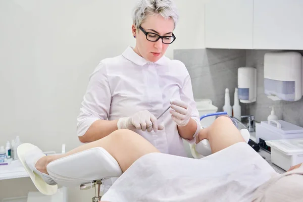 Professionele gynaecoloog onderzoeken vrouwelijke patiënt op gynaecologische stoel met een tang — Stockfoto