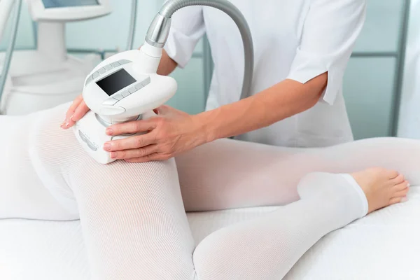 Mujer en traje blanco especial recibiendo masaje anti celulitis para las piernas en un salón de spa. GLP, y tratamiento de contorno corporal en la clínica . —  Fotos de Stock