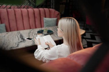 Hayalperest genç kadın, gelecekte kafeteryada dinlenen planlarını ve hedeflerini yazıyor.