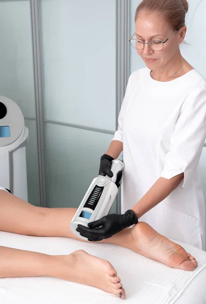 Kosmetolog w gumowych rękawiczkach wykonujący terapię endoferyczną na kobiecych nogach — Zdjęcie stockowe
