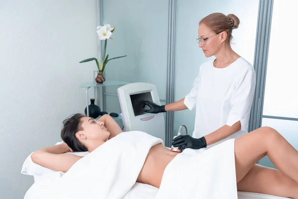 Beautiful woman having cavitation, procedure removing cellulite on legs and belly at beauty clinic — Stock Photo, Image