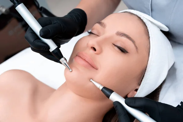 Kosmetologii. Piękna kobieta w spa Clinic odbieranie stymulowanie elektryczne leczenie twarzy od terapeuty. Zbliżenie młoda kobieta twarz podczas Microcurrent Therapy — Zdjęcie stockowe