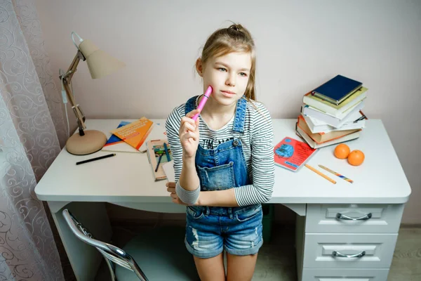 Nastolatka stojąca przy stole i marząca o przerwie w odrabianiu lekcji — Zdjęcie stockowe