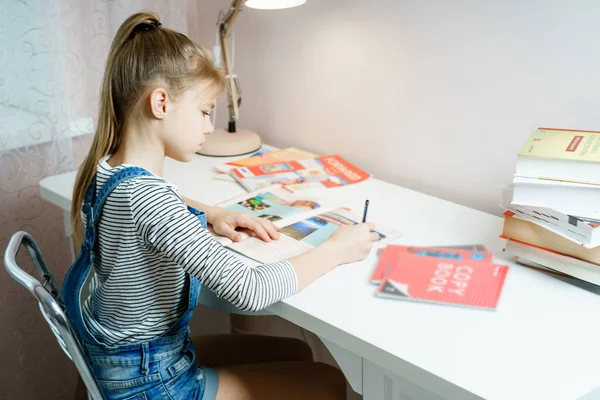 Дівчина-підліток робить домашнє завдання за столом вдома, готуючись до шкільного тесту — стокове фото