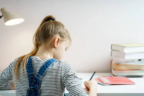 Дівчина-підліток робить домашнє завдання за столом вдома, готуючись до шкільного тесту — стокове фото