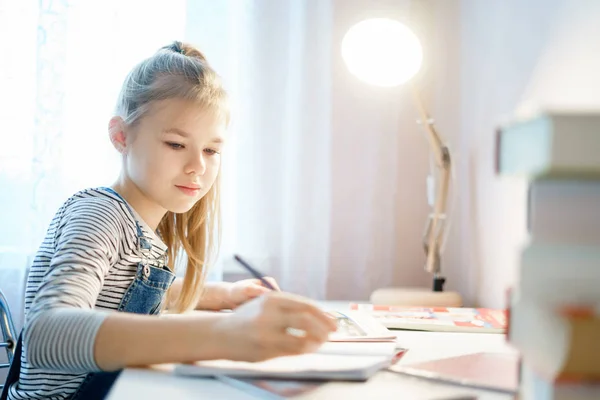 Teenage girl doing homework at table at home preparing for school test — Stock Photo, Image