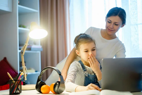 Anne, okul ödevlerini yaparken genç kızın bilgisayar çalışmasına yardım ediyor. — Stok fotoğraf