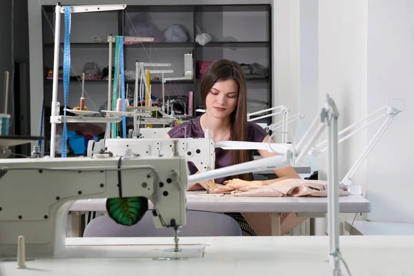 Young dressmaker sew clothes on sewing machine in tailor shop — Stock Photo, Image