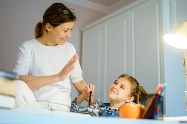 Mother helps daughter with homework while having fun — Stock Photo, Image