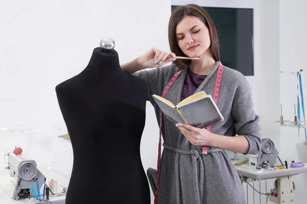 Brunette seamstress measuring black dummy in workshop, tailor studio work — Stock Photo, Image