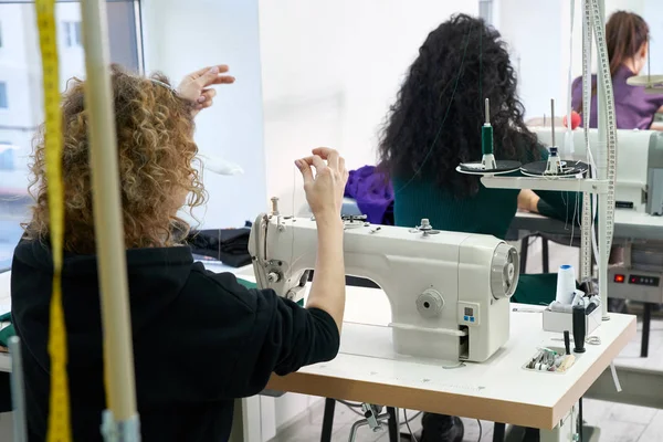 Fiatal szabók varrnak ruhákat varrógépen műtermi stúdióban — Stock Fotó