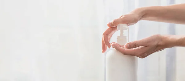 Woman hands pushing pump plastic soap bottle on white background with copy space — 스톡 사진