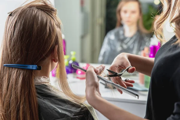 Hairdresser cut hair of a blonde young woman in hair salon — Stock Photo, Image