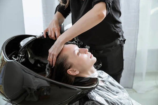 Haar stylist wassen haar van yong blond meisje in kapsalon voor kapsel — Stockfoto