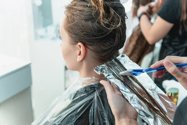 woman having hair foiled while coloring in hair salon