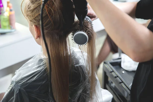 Bliska rąk fryzjerów suszarka długie blond włosy z suszarki i szczotki okrągłe — Zdjęcie stockowe
