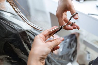 Hairdresser cut hair of a blonde young woman in hair salon