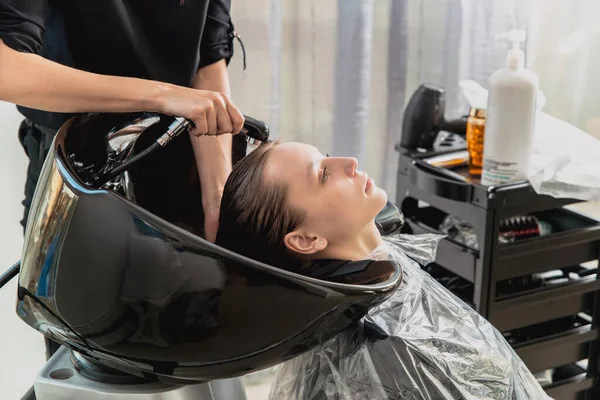 Haar stylist wassen haar van yong blond meisje in kapsalon voor kapsel — Stockfoto