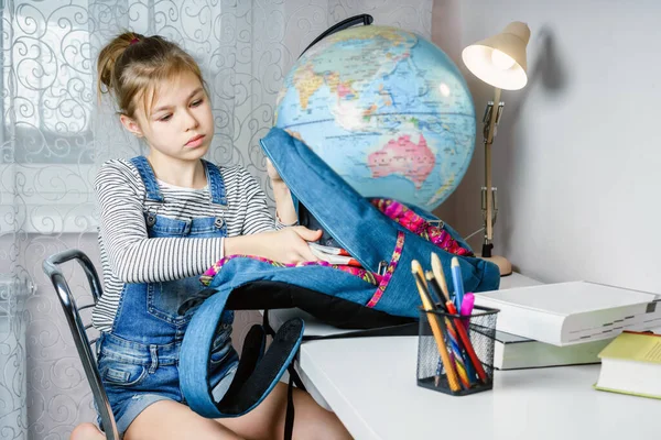 Preteen ragazza imballaggio roba nello zaino a tavola per la scuola dopo aver finito i compiti — Foto Stock