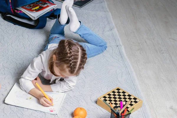 Cute little girl jest rysunek na podłodze w salonie — Zdjęcie stockowe