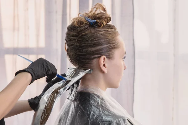 Hairdresser coloring young woman hair using foil — Stock Photo, Image