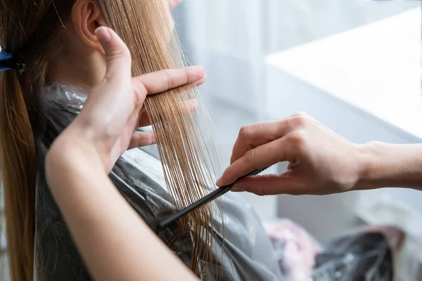 Hairdresser brushing long blonde hair with brush in beauty salon — Stock Photo, Image