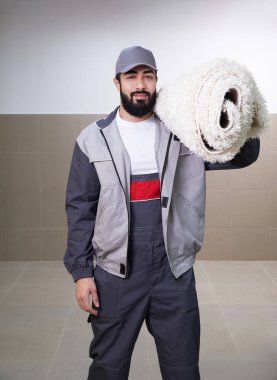 Man wearing uniform standing with a roll of carpet on his shoulder