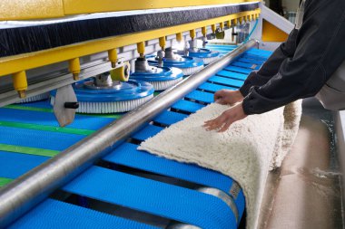 Çamaşır işçisi, kuru temizlemedeki halı yıkama için otomatik makine üzerinde çalışıyor.