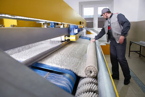 Laundry worker in the process of working on automatic machine for carpet washing in dry cleaning — Stock Photo, Image