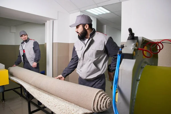 Uomini lavoratori ottenere tappeto da una lavatrice automatica e mettere in asciugatrice nel servizio di lavanderia — Foto Stock