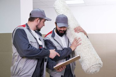 Two men taking away big carpet for cleaning service