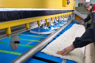 Çamaşır işçisi, kuru temizlemedeki halı yıkama için otomatik makine üzerinde çalışıyor.