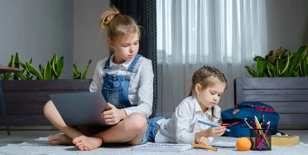 Două surori întinse pe podea în sufragerie folosind laptop, jucând și desenând — Fotografie, imagine de stoc