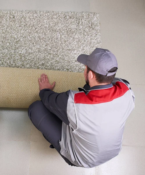 Male Worker Unrolling Carpet On Floor At Home, view from above — Stok fotoğraf