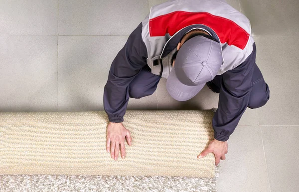 Hombre trabajador desenrollando alfombra en el suelo en casa, vista desde arriba —  Fotos de Stock