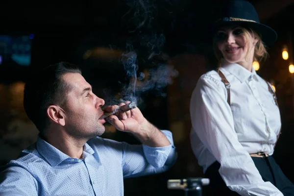 Mannen-gangstern och den vackra äldre kvinnan röker cigarr i en bar — Stockfoto