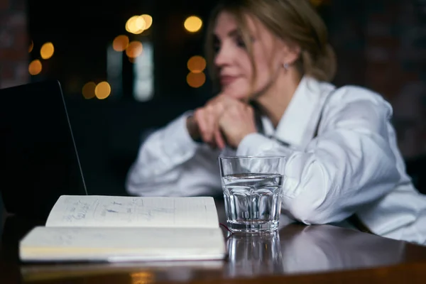 Krásná starší žena pracující v kavárně s notebookem a psaní v notepadu — Stock fotografie