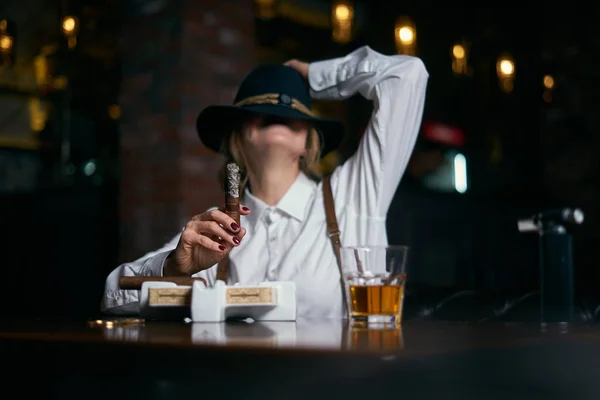 Senior attraktiv kvinnlig gangster rökning cigarr över mörk bakgrund i restaurang — Stockfoto