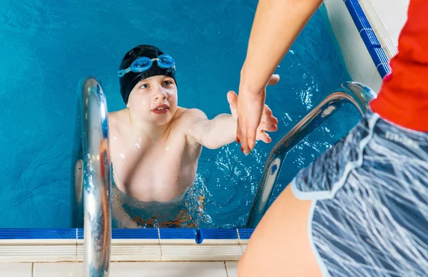 Жінка тренер у воді дає хлопчик плавання Урок у критому басейні — стокове фото