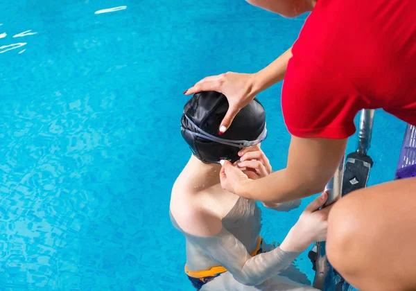 Vrouwelijke coach in het water geven tiener jongen zwemmen les in overdekt zwembad — Stockfoto