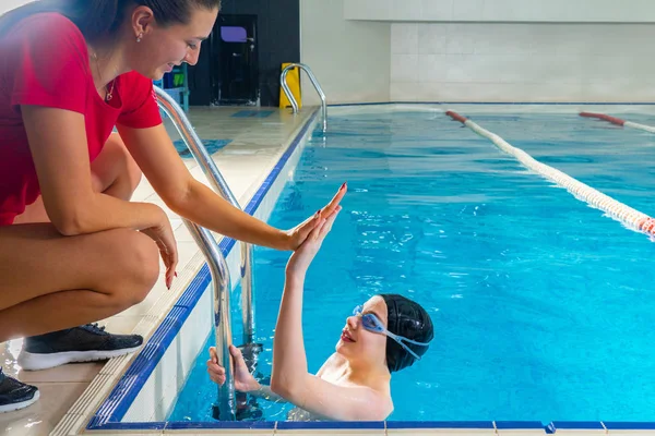 Kobieta trener w wodzie dając nastolatek chłopiec pływanie Lekcja w kryty basen — Zdjęcie stockowe