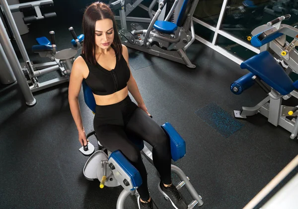 Jovem mulher fitness executar exercício com máquina no ginásio — Fotografia de Stock
