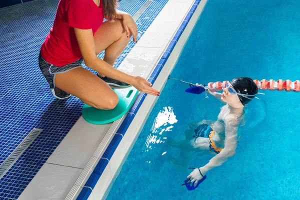 Vrouwelijke coach in het water geven tiener jongen zwemmen les in overdekt zwembad — Stockfoto