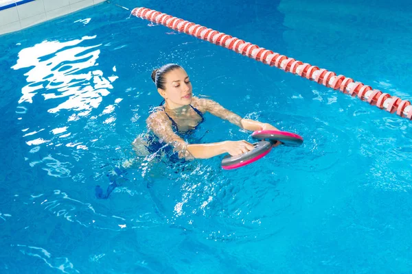 Jonge vrouw doet water aerobics in overdekt zwembad, sportief concept — Stockfoto