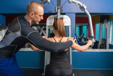 Modern spor salonunda genç bir kadınla çalışan özel antrenör.