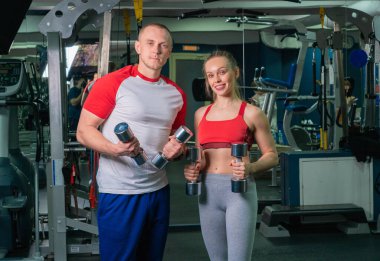 Modern spor salonunda genç bir kadınla çalışan özel antrenör.